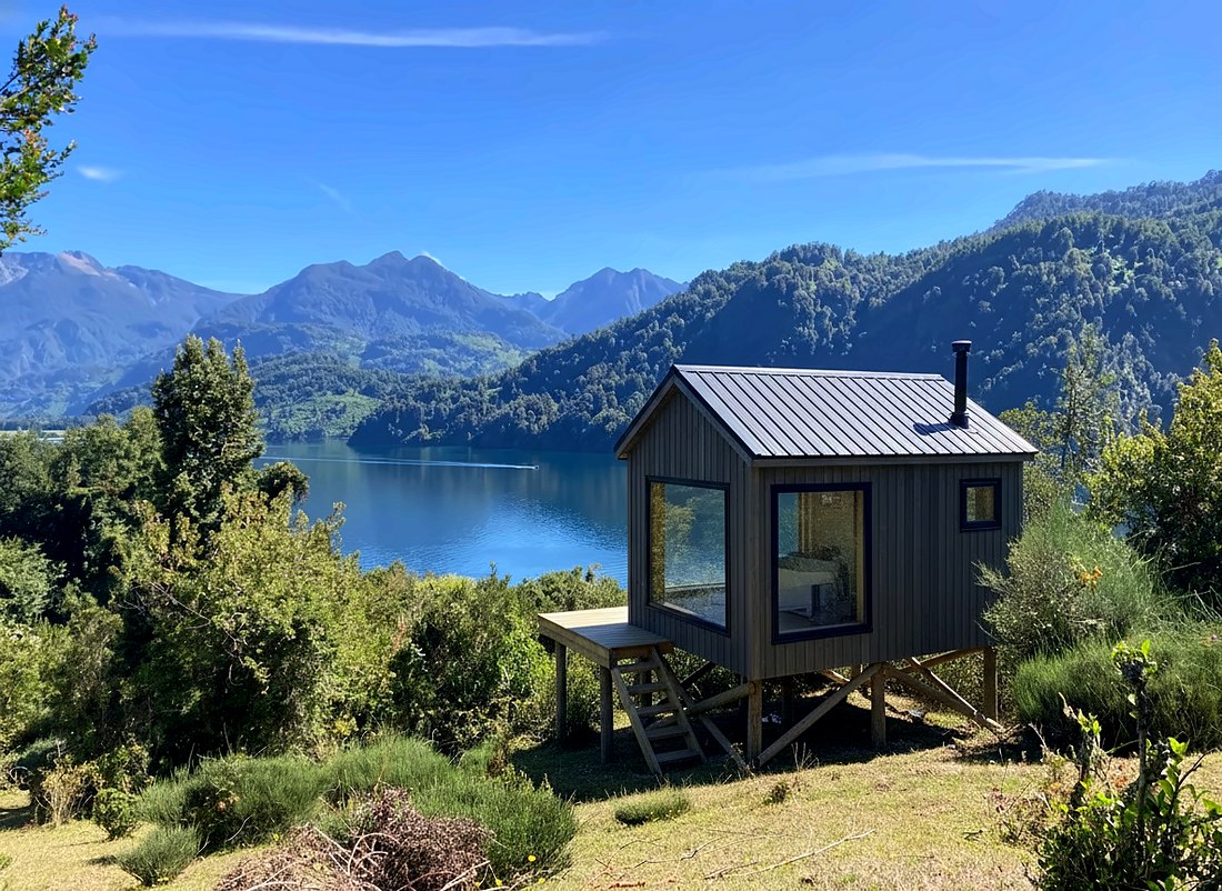 Tiny house Modus Patagonia sobre pilotes frente a un lago, con cordillera de fondo